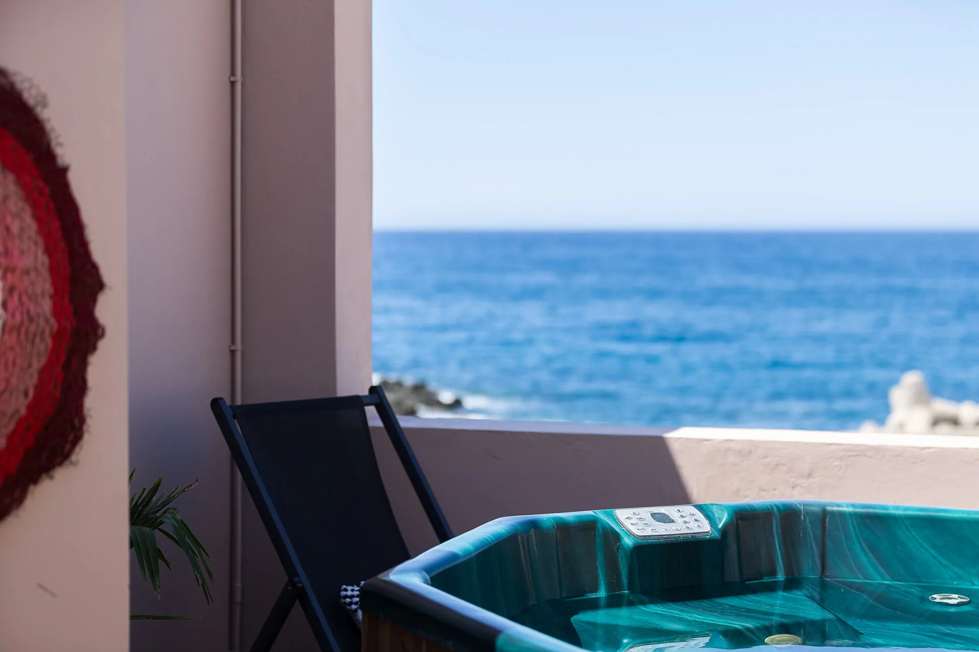 The private hot tub on the Evexia terrace, painted Cretan tiles behind it and the sea beyond